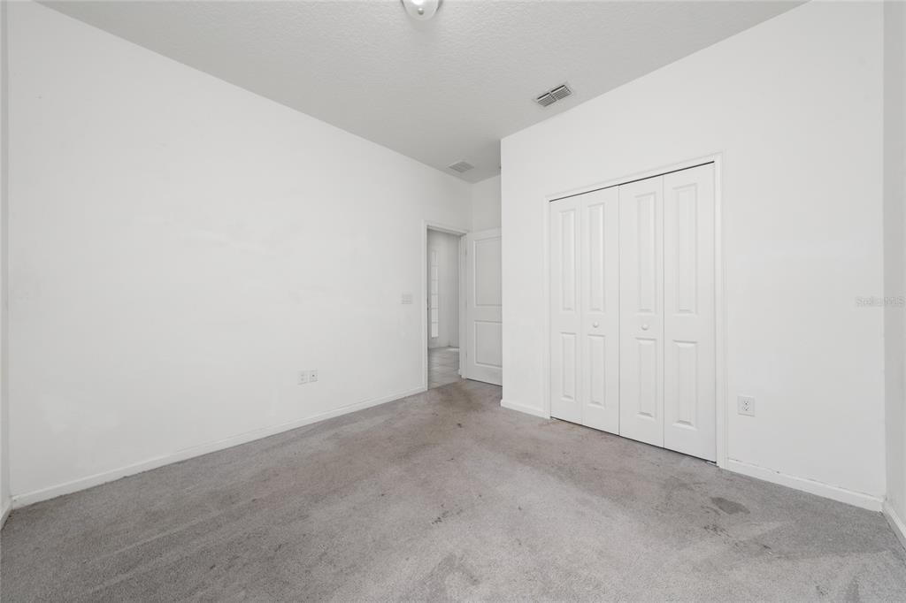 An empty bedroom features white walls, gray carpeting, and a white bi-fold closet door — 417 SAPPHIRE DRIVE, DAVENPORT, FL