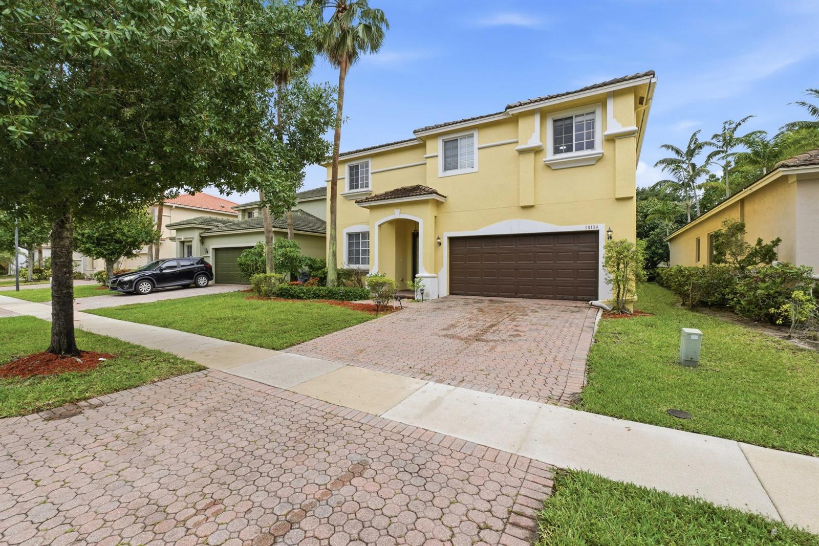 A two-story yellow house with a brown garage door and a brick driveway — 10134 Boca Vista Drive, Boca Raton FL 33498, BOCA RATON, FL