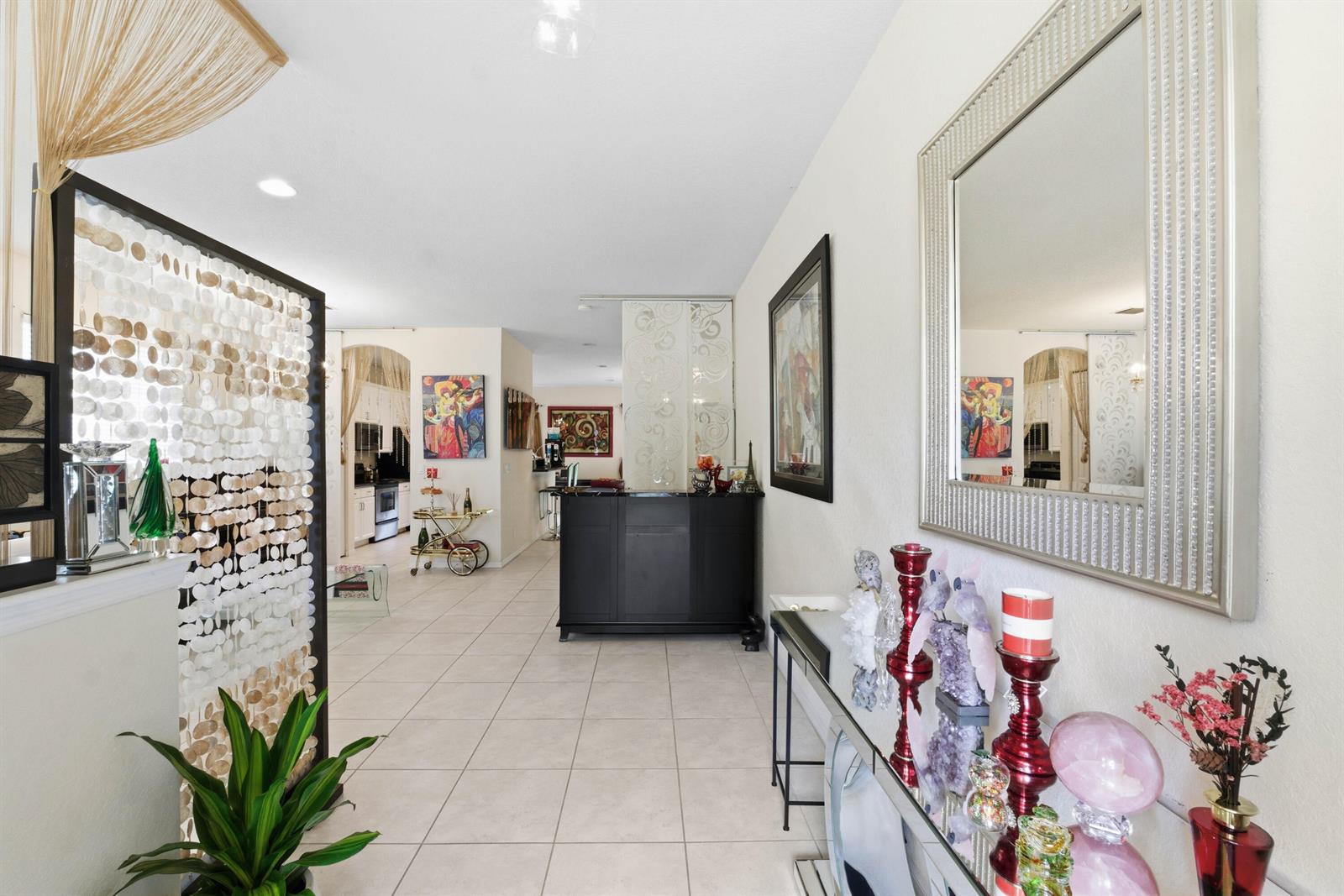 A tiled hallway leads to an open living area featuring a bar and decorative room dividers — 10134 Boca Vista Drive, Boca Raton FL 33498, BOCA RATON, FL