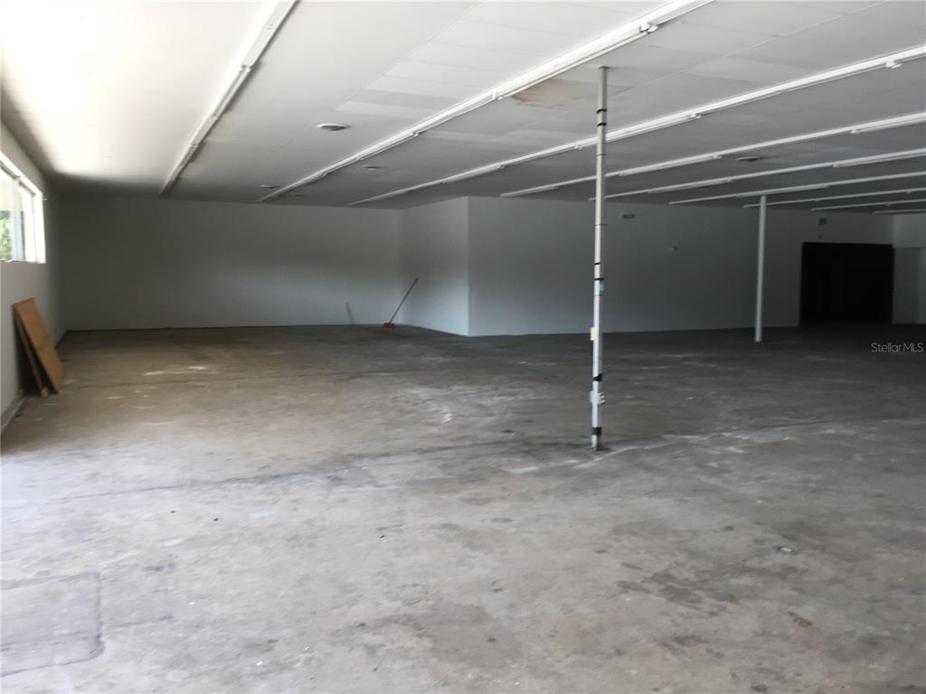 An empty commercial space features a concrete floor, white walls, and a drop ceiling — 2915 NE JACKSONVILLE ROAD, OCALA, FL