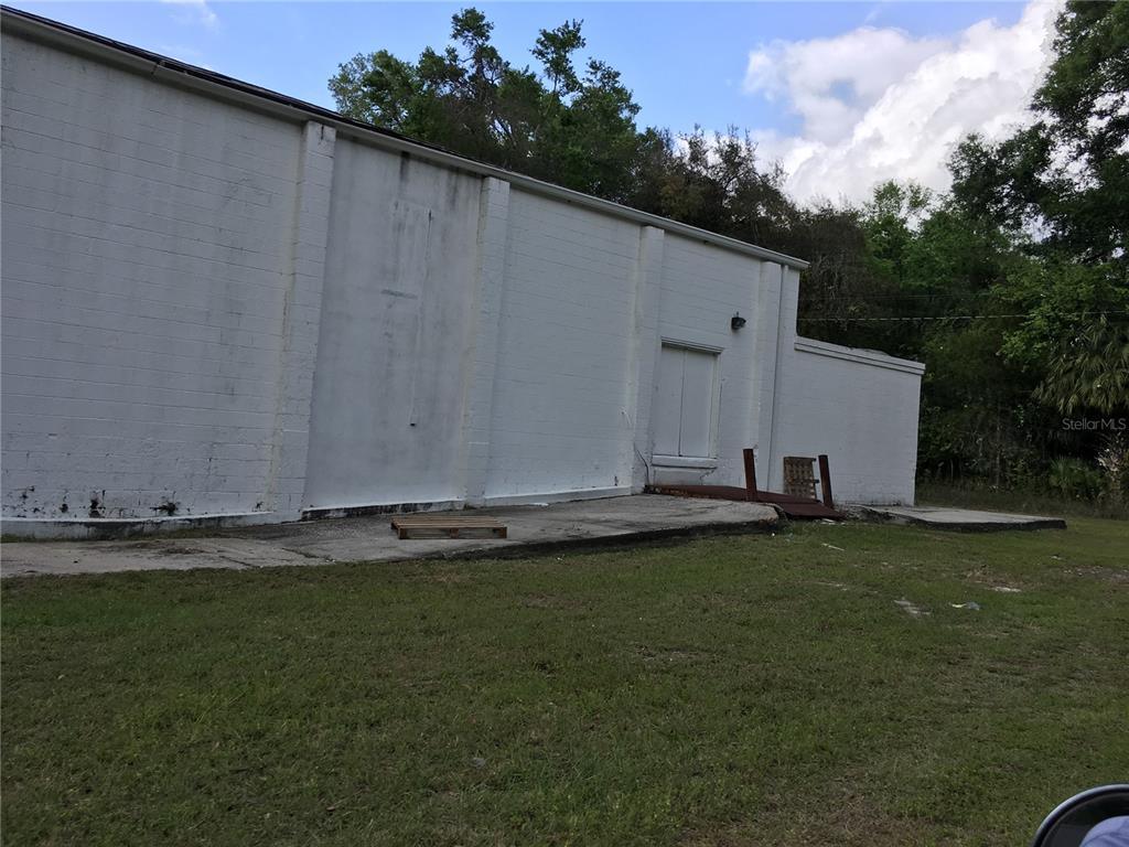 The exterior of a white concrete block building features a loading dock and ramp — 2915 NE JACKSONVILLE ROAD, OCALA, FL
