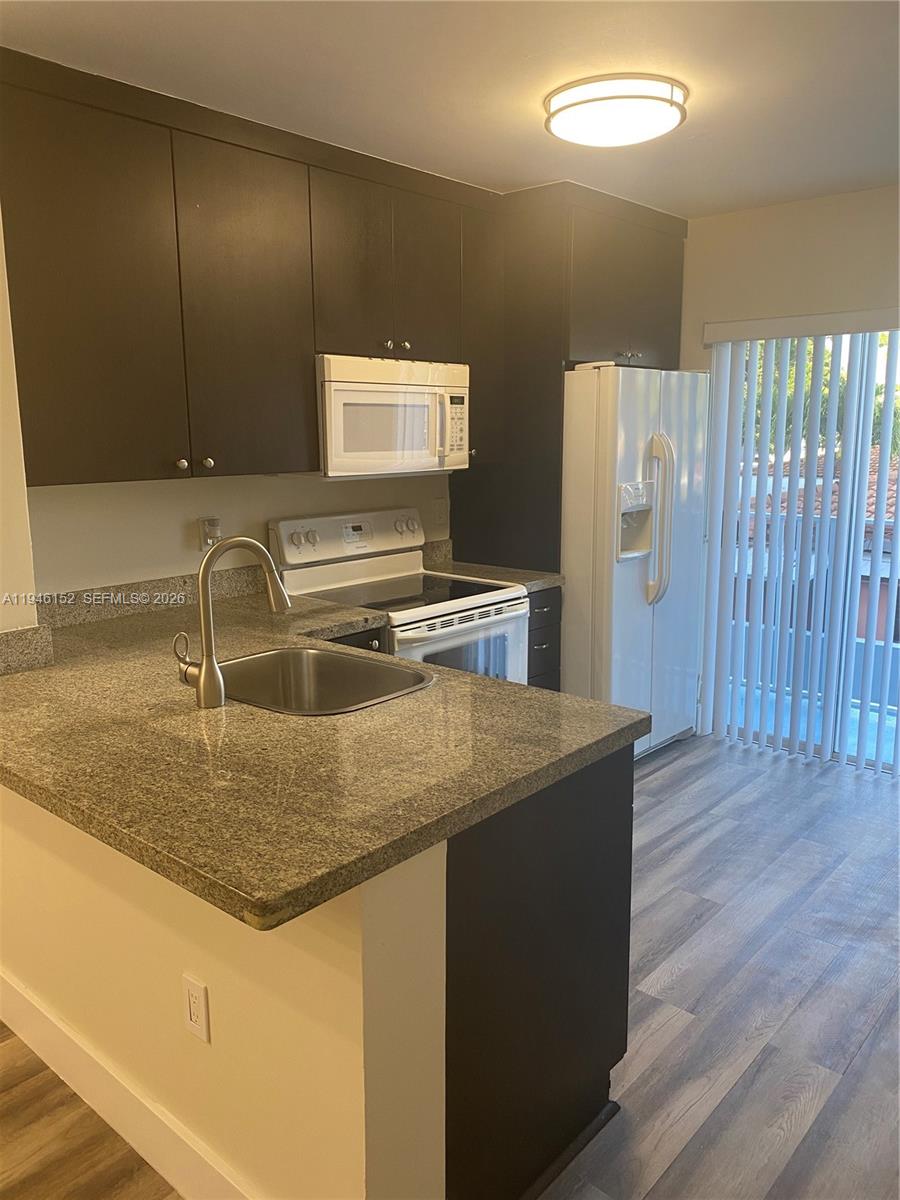 A kitchen features dark cabinets, granite countertops, a stainless steel sink, and white appliances — 2575 SW 27th Ave # 212, Coconut Grove FL 33133, COCONUT GROVE, FL