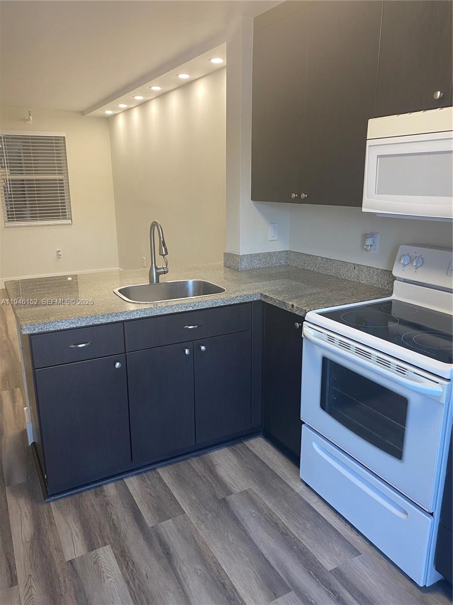 A kitchen features dark wood cabinets, granite countertops, and white appliances — 2575 SW 27th Ave # 212, Coconut Grove FL 33133, COCONUT GROVE, FL