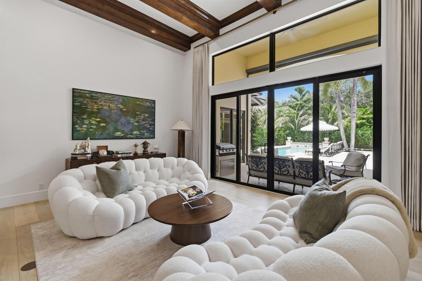 A living room features two white tufted sofas, a round wooden table, and sliding glass doors — 147 Segovia Way, Jupiter FL 33458, JUPITER, FL