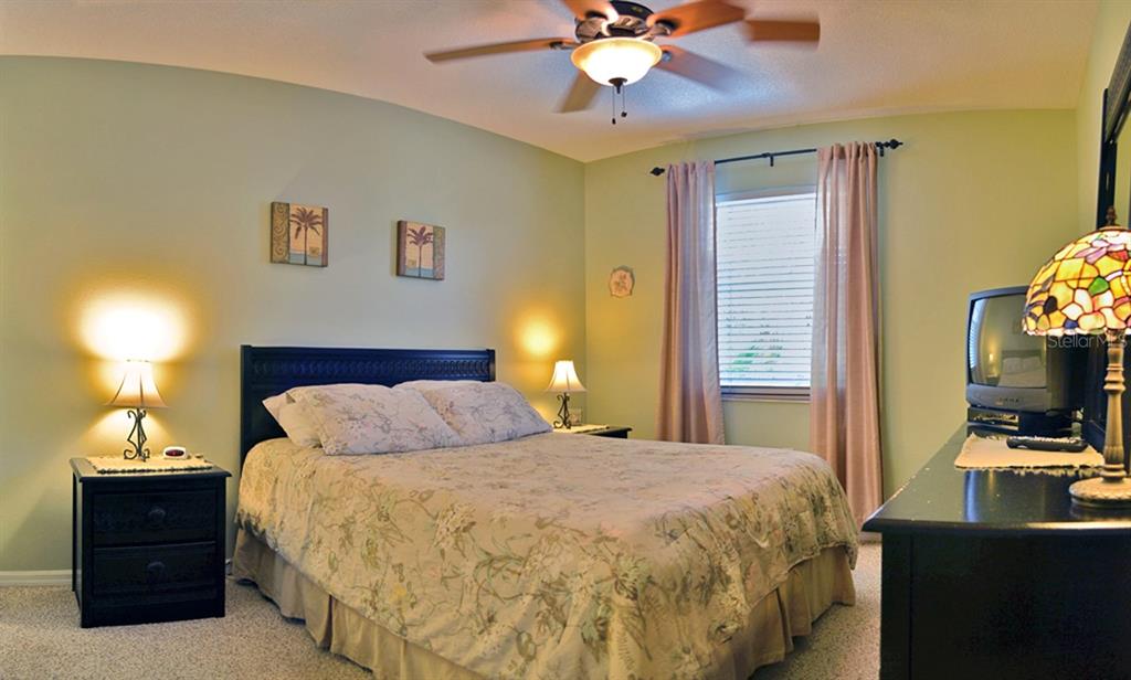 A bedroom features a queen bed, two nightstands, a ceiling fan, and a television — 5157 SANDY BEACH AVENUE, SARASOTA, FL
