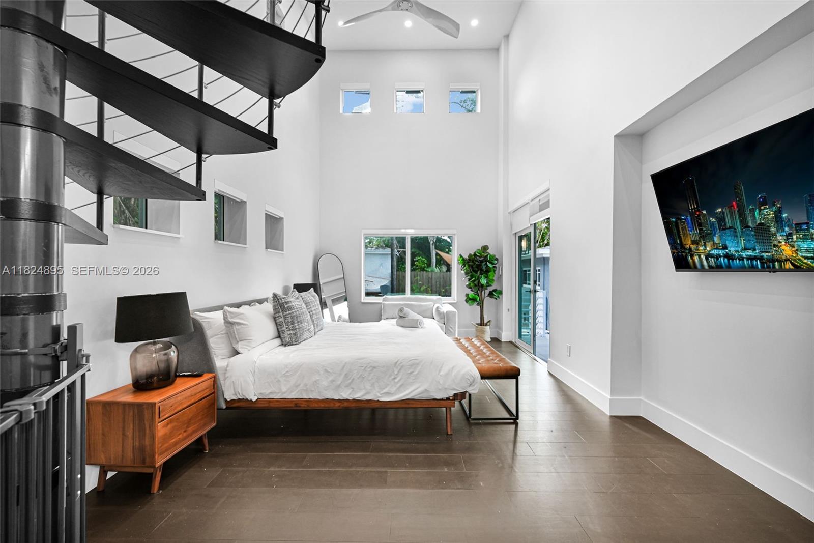 A modern bedroom features a spiral staircase, high ceilings, and a wall-mounted television — 150 NE 50 # A, Miami FL 33137, MIAMI, FL