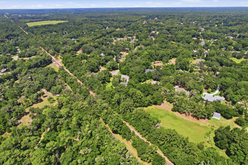 An aerial view shows a wooded residential area with a railroad track and open fields — 18860 SW 99TH STREET, DUNNELLON, FL