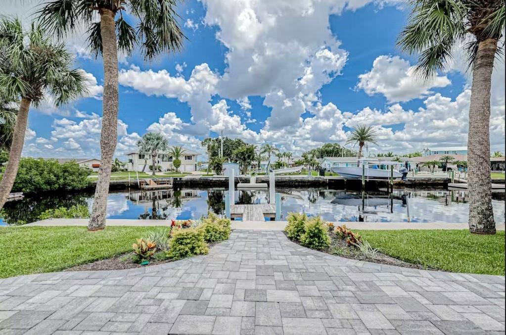 A paved walkway leads to a private boat dock on a canal lined with palm trees — 8116 BRIGHTON DRIVE, PORT RICHEY, FL