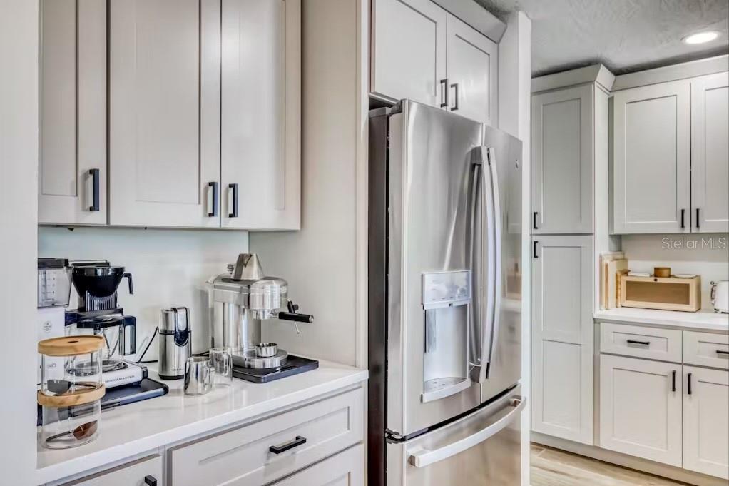 A kitchen features light gray cabinets, stainless steel appliances, and a white countertop coffee station — 8116 BRIGHTON DRIVE, PORT RICHEY, FL