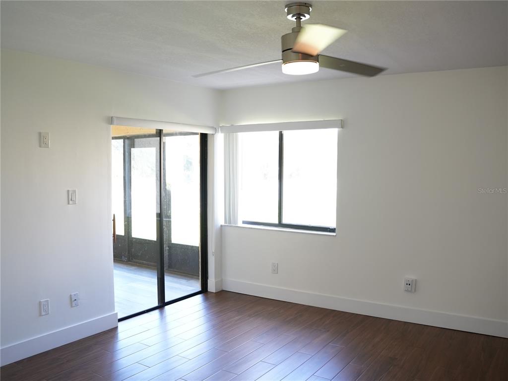 A room with white walls, dark wood-look flooring, a ceiling fan, and sliding glass doors — 4406 S LAKE ORLANDO PARKWAY UNIT 2, ORLANDO, FL