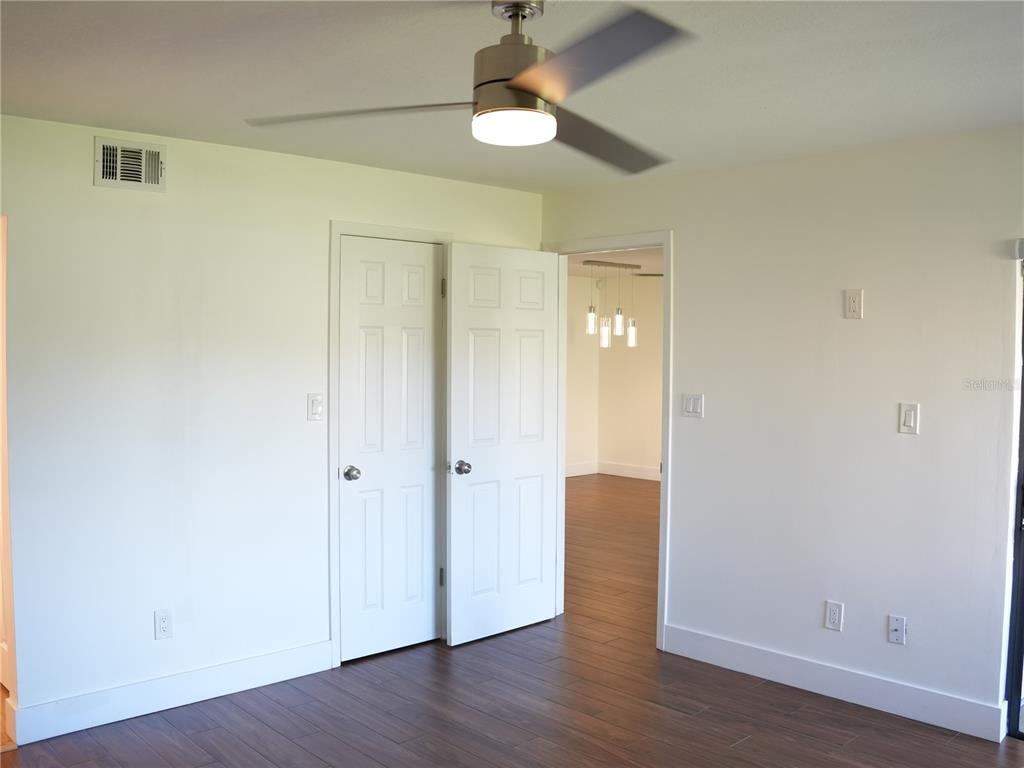 A room with white walls, dark wood-look flooring, a ceiling fan, and double closet doors — 4406 S LAKE ORLANDO PARKWAY UNIT 2, ORLANDO, FL