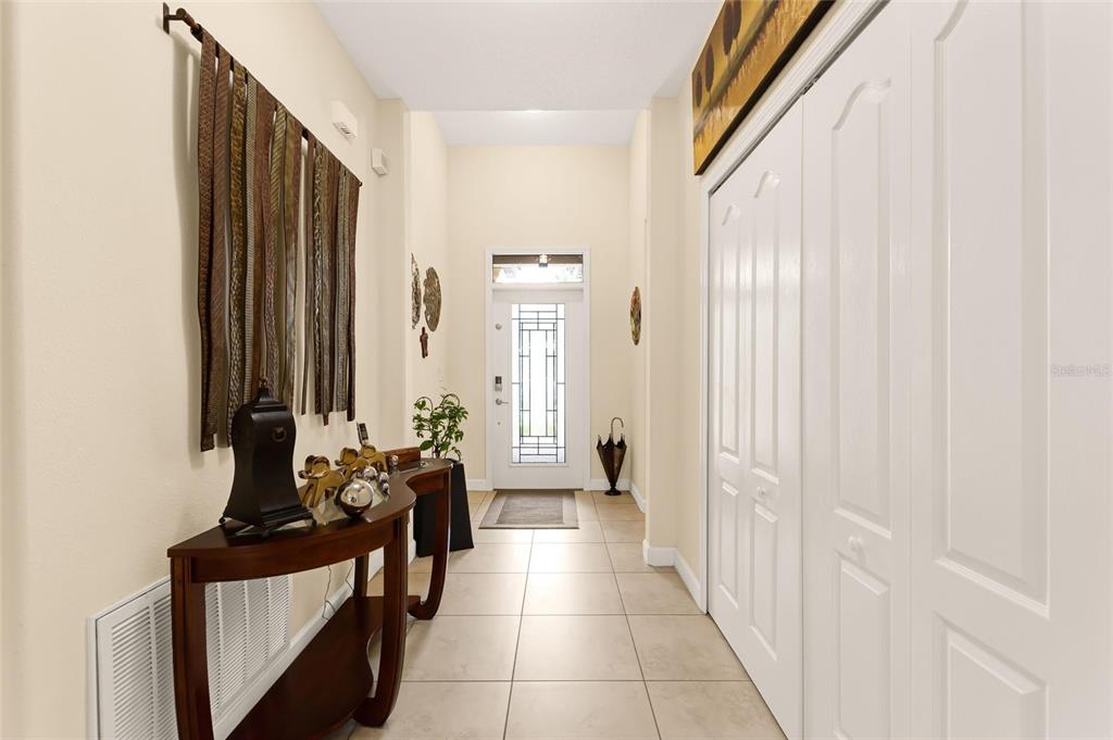 A bright entryway features tiled floors, a wooden console table, and white closet doors — 1353 PALMETTO DUNES ST, DAVENPORT, FL