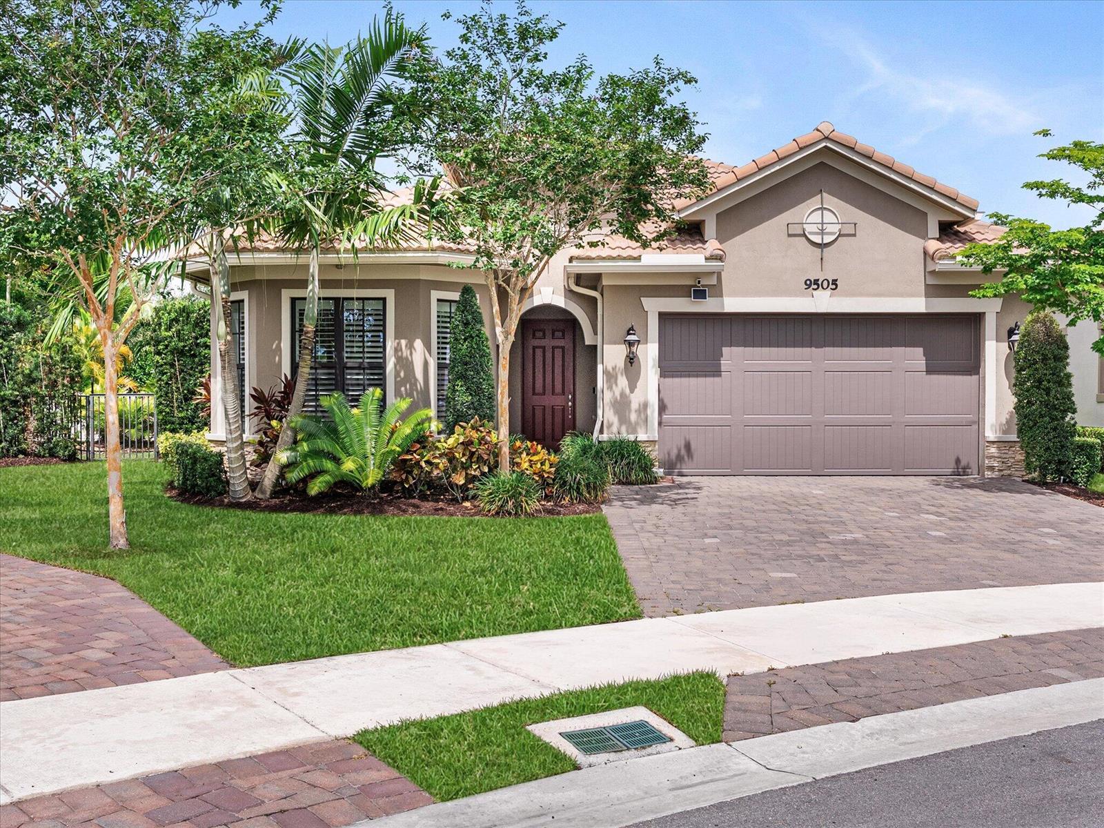 A single-story house with a brown garage door, arched front door, and landscaped front yard — 9505 Kalmar Circle W, Parkland FL 33076, PARKLAND, FL