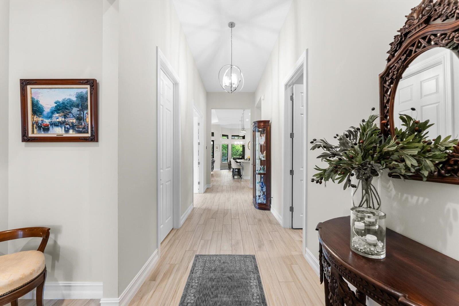 A bright hallway features light wood-look tile flooring, white walls, and a decorative pendant light — 9505 Kalmar Circle W, Parkland FL 33076, PARKLAND, FL