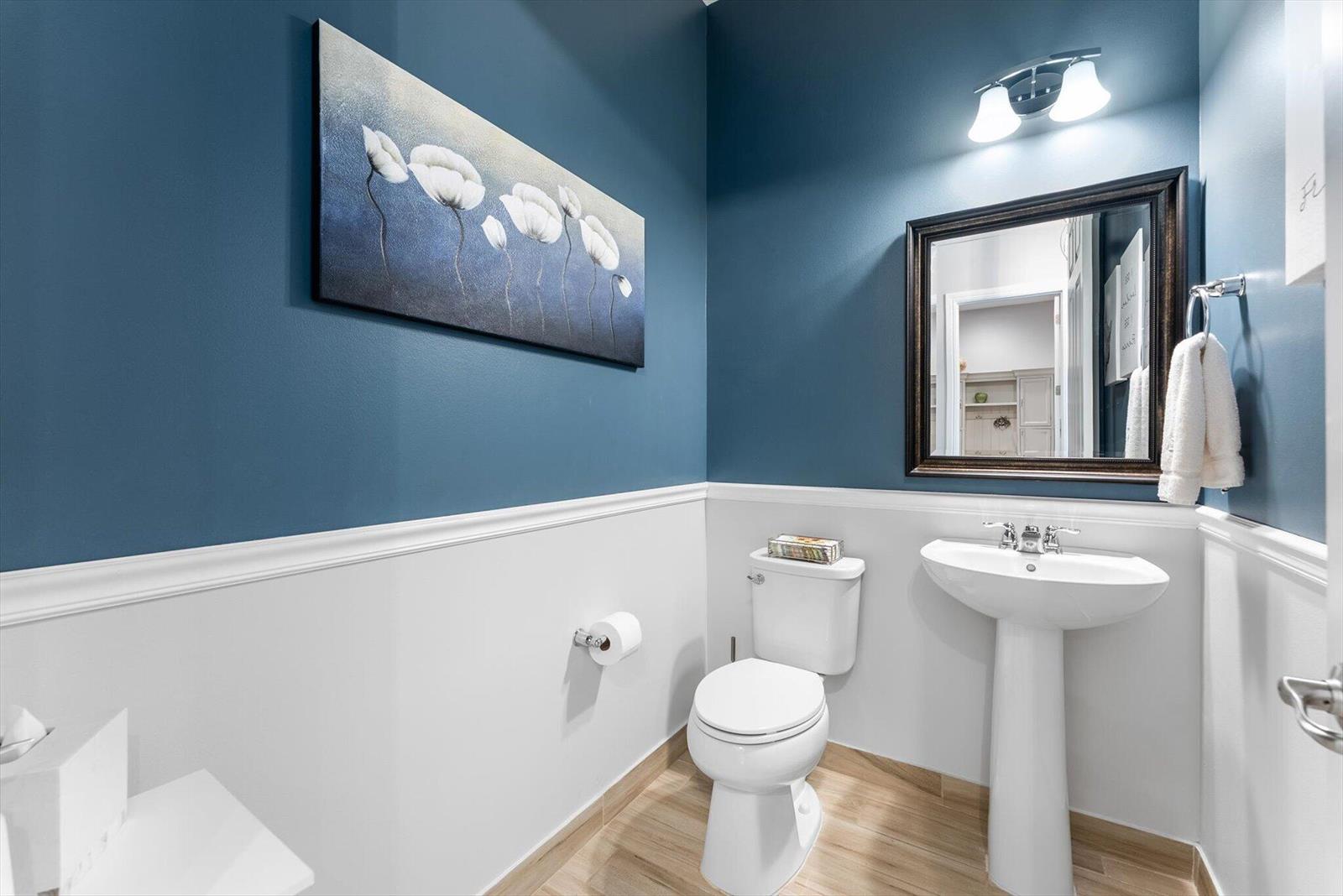A powder room features blue walls, white wainscoting, a pedestal sink, and a toilet — 9505 Kalmar Circle W, Parkland FL 33076, PARKLAND, FL