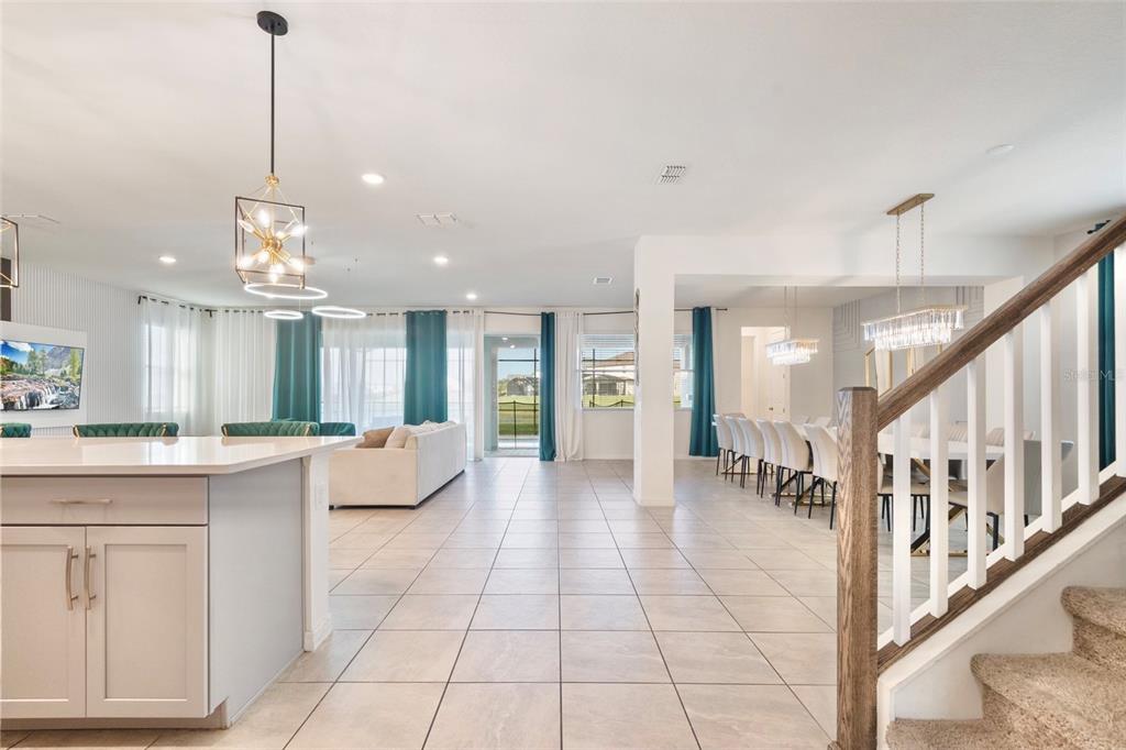 An open-concept living and dining area with tile floors, a kitchen island, and a staircase — 1594 MERMAID COVE WAY, KISSIMMEE, FL