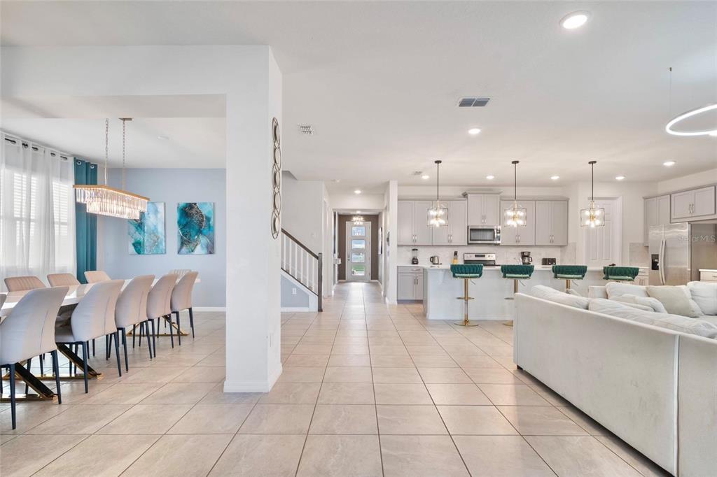 An open-concept living area features a dining room, kitchen with island seating, and tiled floors — 1594 MERMAID COVE WAY, KISSIMMEE, FL