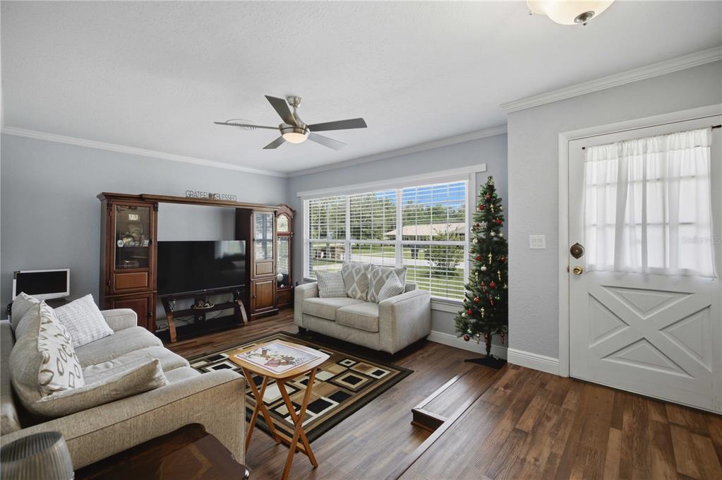 A living room features light gray walls, wood-look flooring, a ceiling fan, and a front door — 4218 SE 14TH PLACE, OCALA, FL