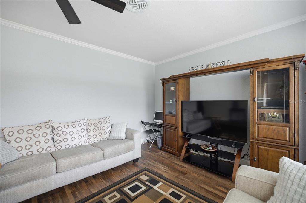 A living room features a gray sofa, a large wooden entertainment center, and wood flooring — 4218 SE 14TH PLACE, OCALA, FL