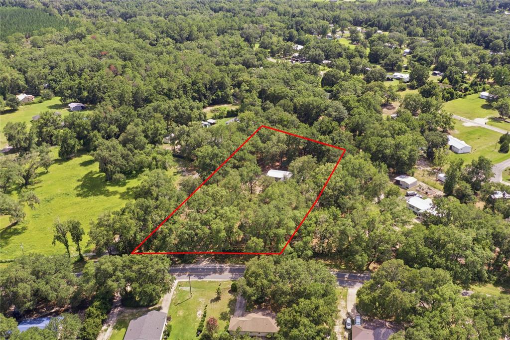 An aerial view shows a wooded lot outlined in red with a small house inside — 2876 SE COUNTY ROAD 245, LAKE CITY, FL