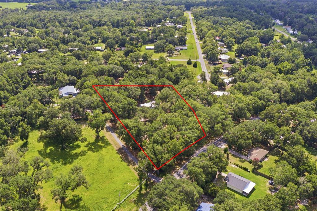 An aerial view shows a wooded residential lot outlined in red next to a road — 2876 SE COUNTY ROAD 245, LAKE CITY, FL