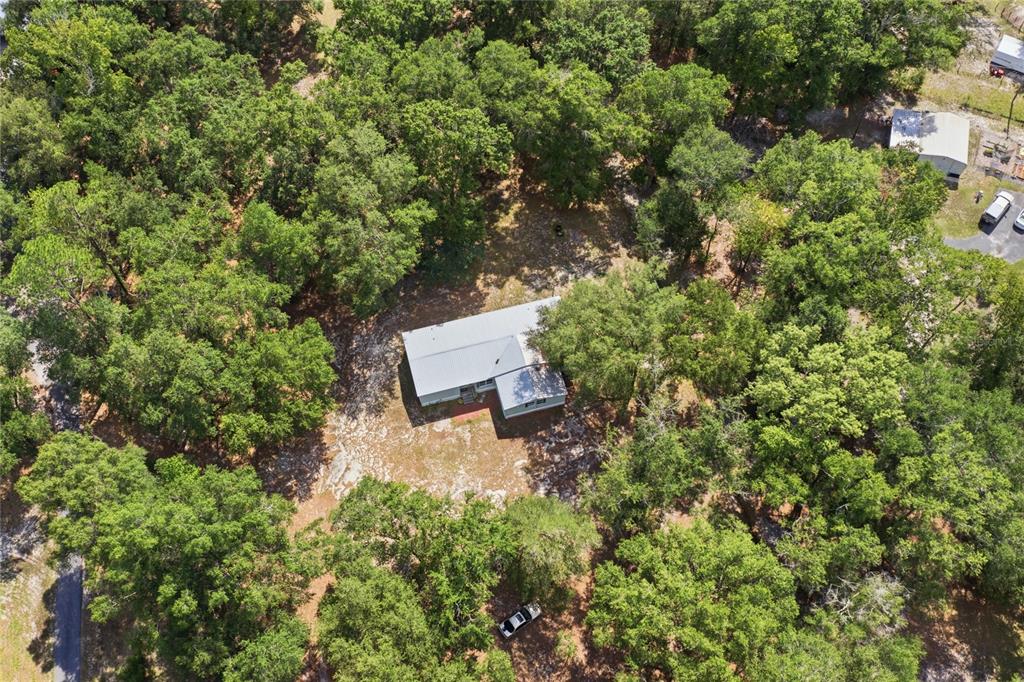 An aerial view shows a house with a metal roof surrounded by dense trees — 2876 SE COUNTY ROAD 245, LAKE CITY, FL