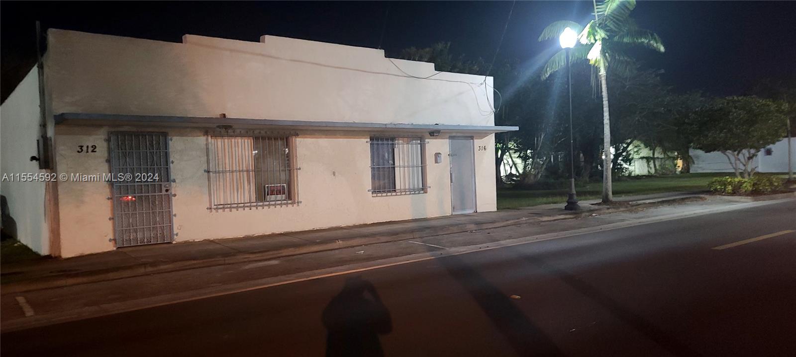 A single-story commercial building with two entrances and security bars on the windows at night — 312 SW 4 ST, Homestead FL 33030, HOMESTEAD, FL