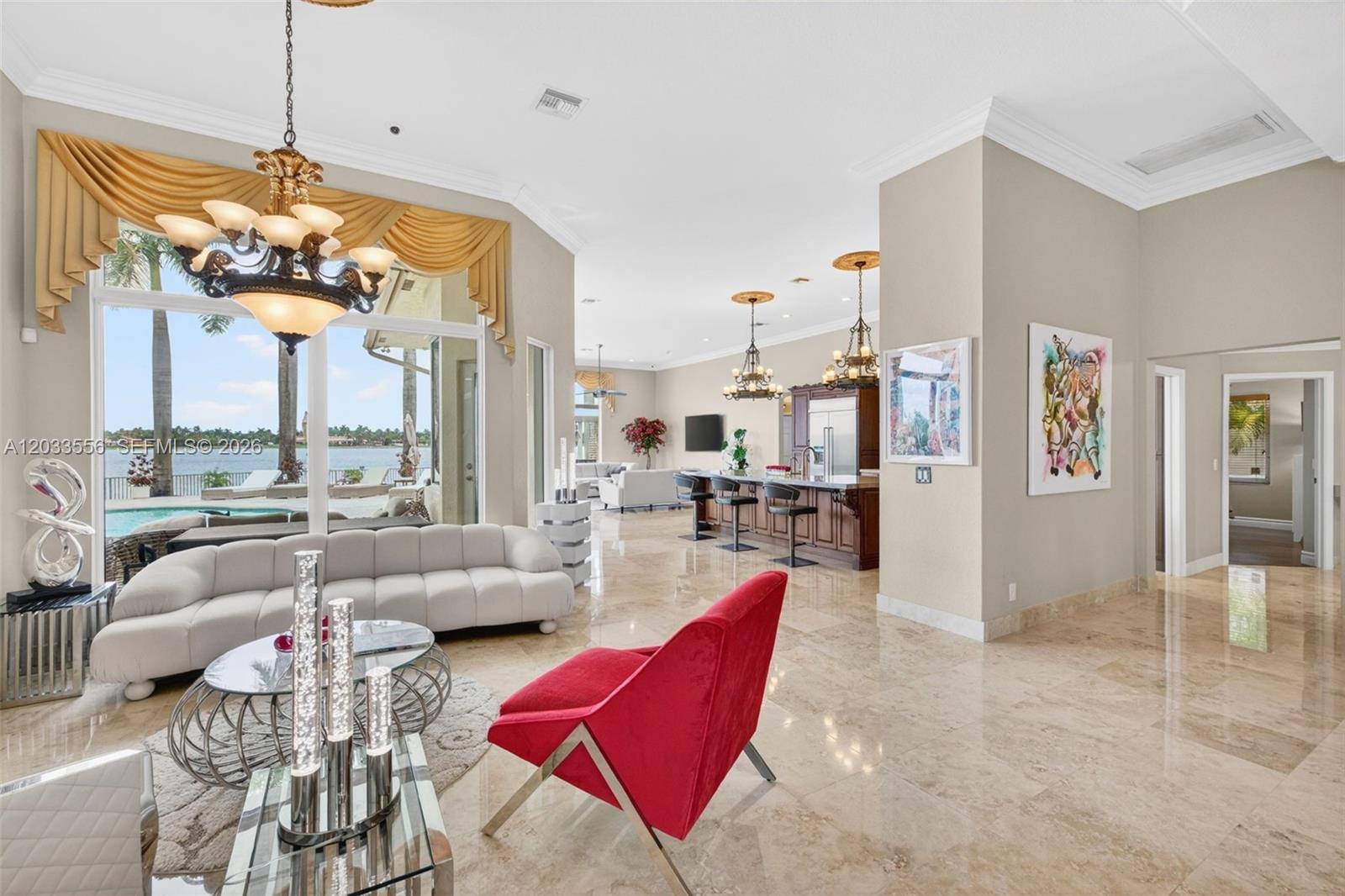 An open-concept living room and kitchen feature marble floors, a chandelier, and waterfront pool views — 18611 SW 39th St, Miramar FL 33029, MIRAMAR, FL