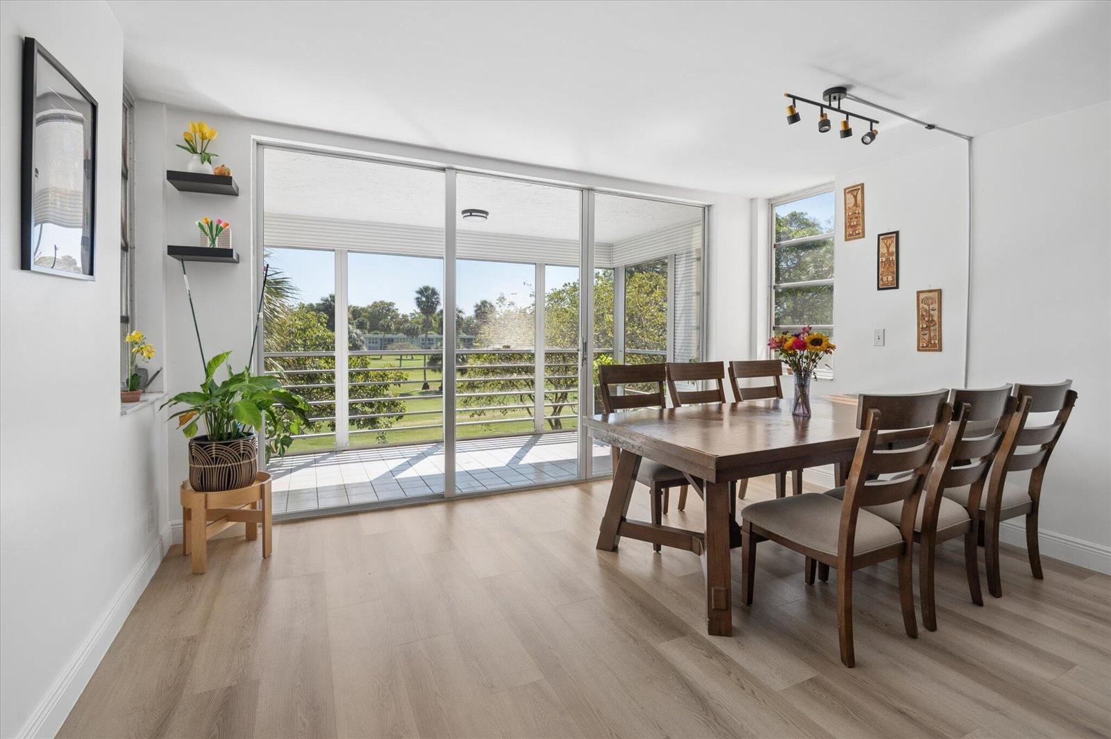 A dining room with a wooden table, six chairs, light wood floors, and a balcony view — 804 Cypress Grove Lane # 308, Pompano Beach FL 33069, POMPANO BEACH, FL
