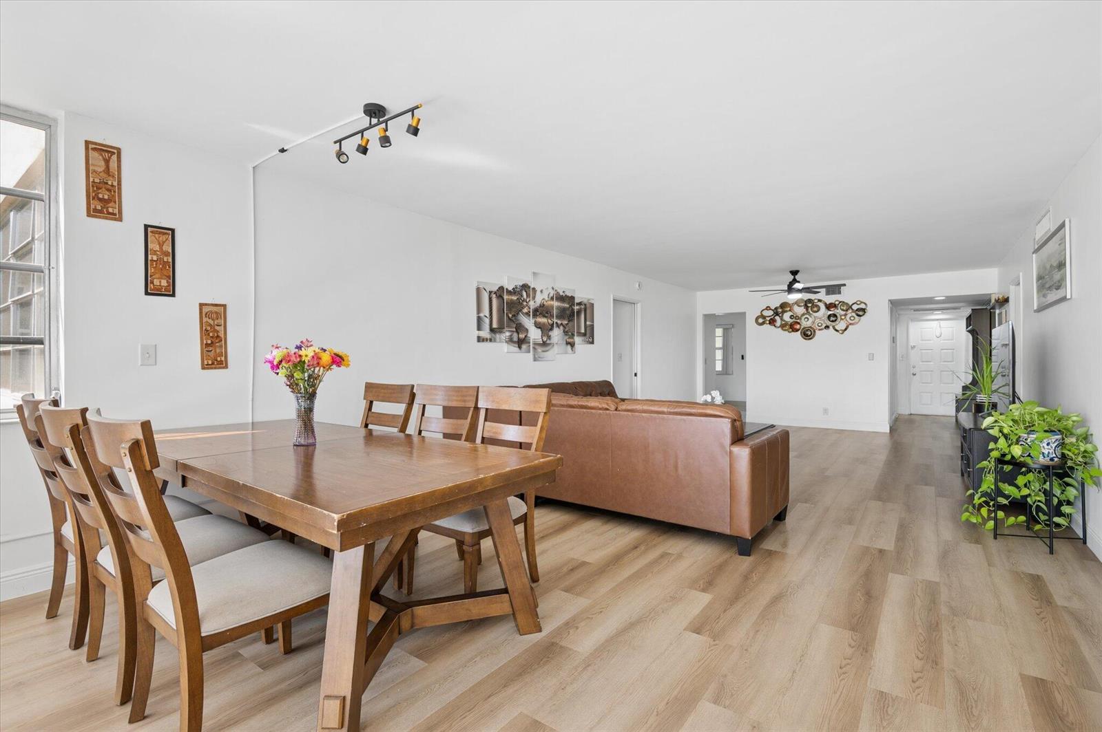 A dining area with a wooden table and chairs opens into a living room space — 804 Cypress Grove Lane # 308, Pompano Beach FL 33069, POMPANO BEACH, FL
