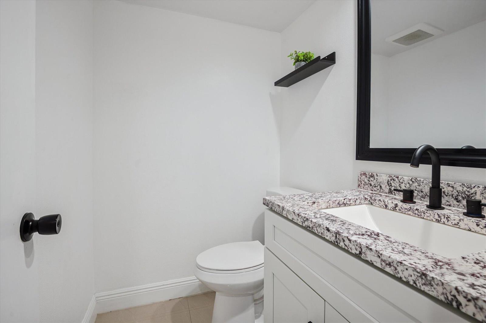 A bathroom features a white vanity with granite countertop, black fixtures, and a wall-mounted shelf — 804 Cypress Grove Lane # 308, Pompano Beach FL 33069, POMPANO BEACH, FL