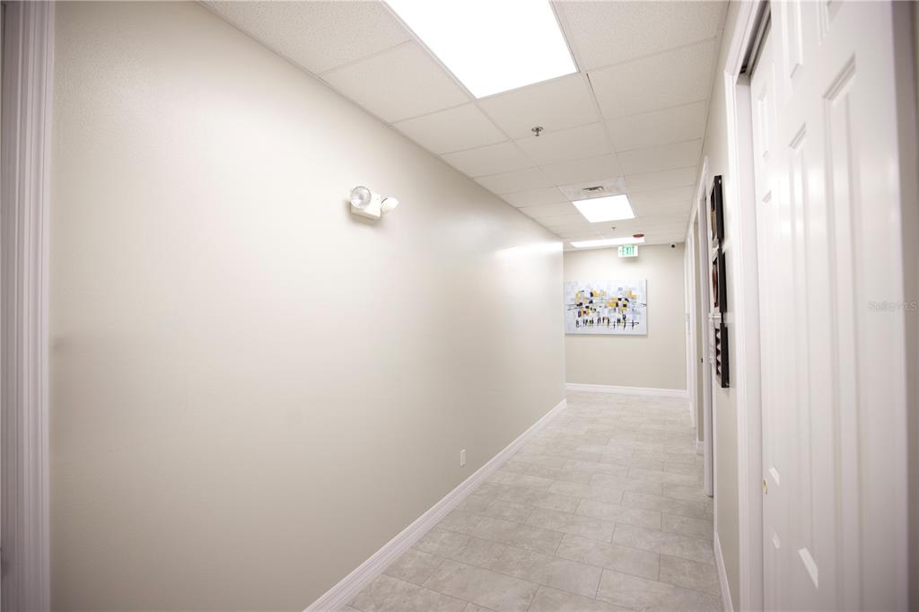 A brightly lit office hallway features light-colored walls, tile flooring, and a drop ceiling — 21942 EDGEWATER DRIVE, PORT CHARLOTTE, FL