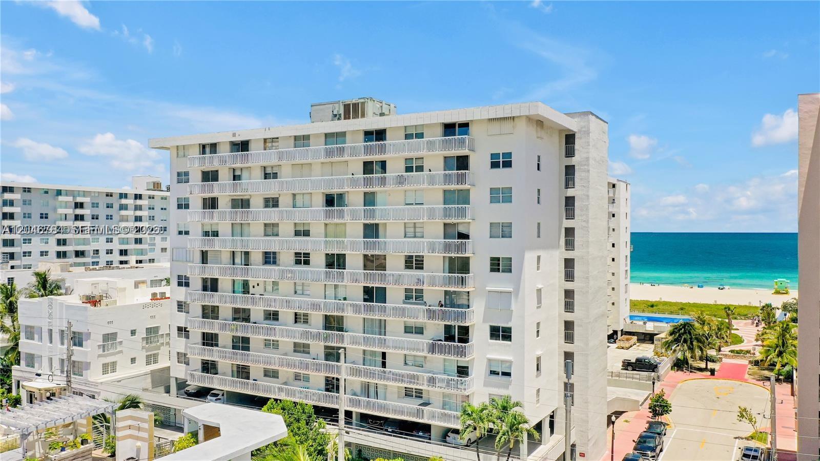 An exterior view of a multi-story white apartment building located near a sandy beach — 401 Ocean Dr # 722, Miami Beach FL 33139, MIAMI BEACH, FL