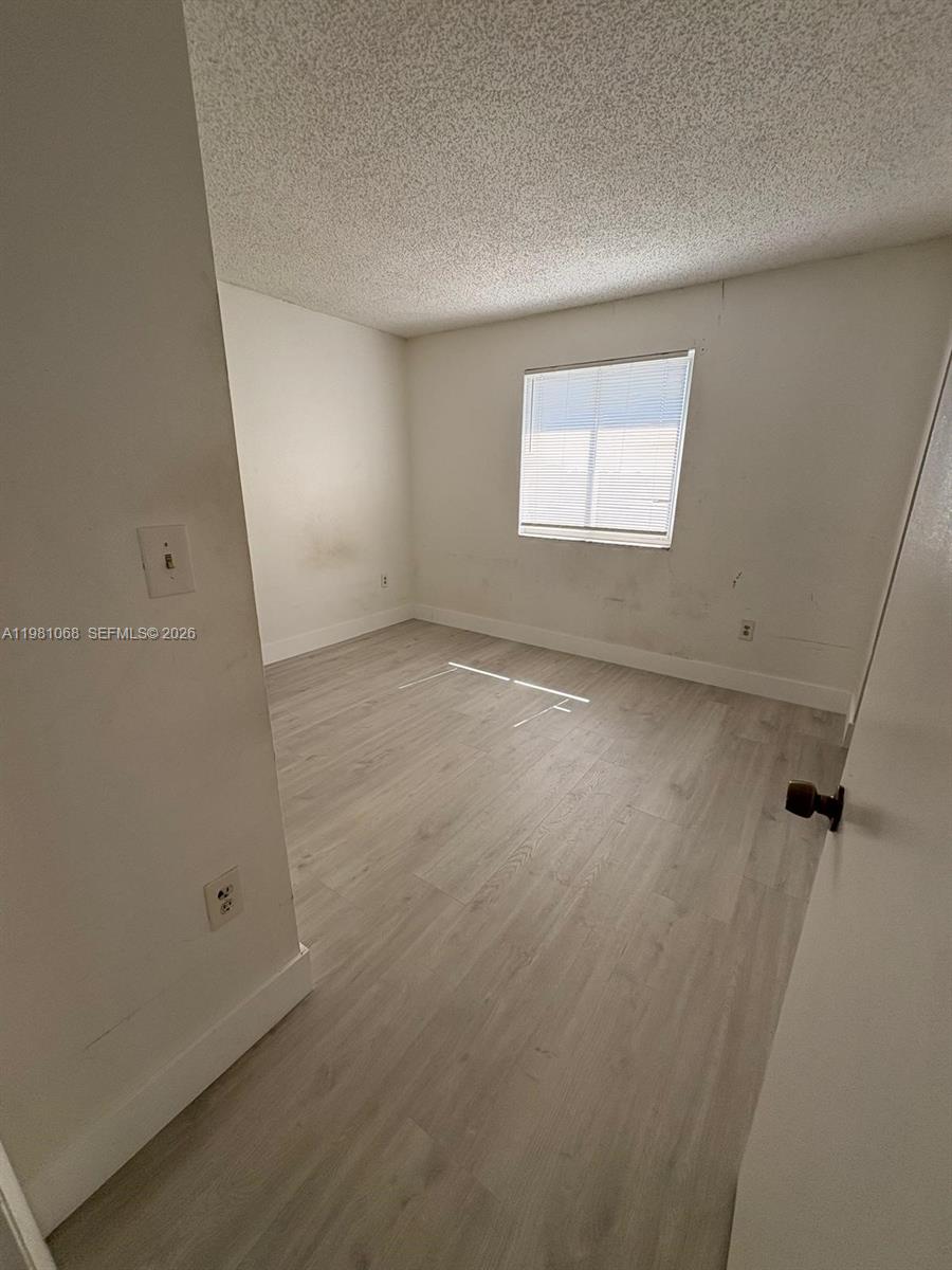 An empty bedroom features light-colored wood-look flooring, white walls, and a single window — 15231 SW 80th St # 615, Miami FL 33193, MIAMI, FL