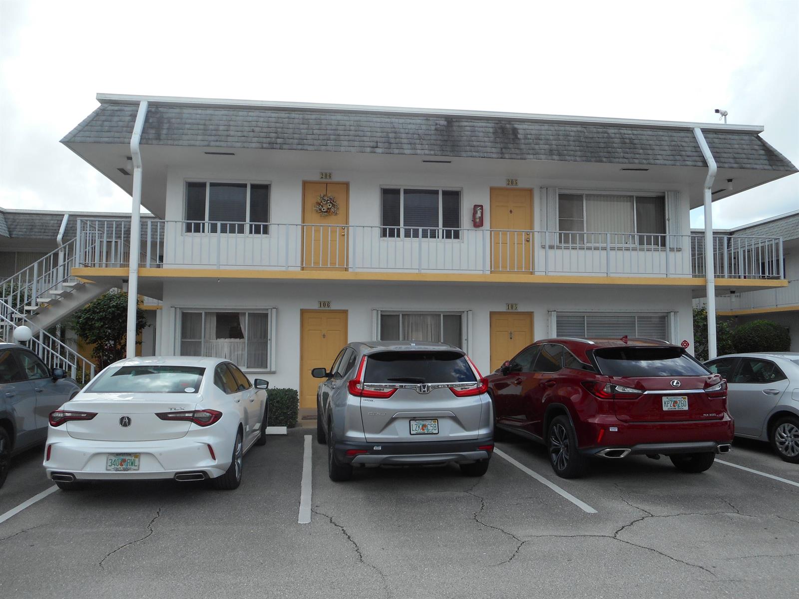 A two-story motel building with yellow doors and parked cars in front — 3322 Cynthia Lane # 106, FL 33461, FL