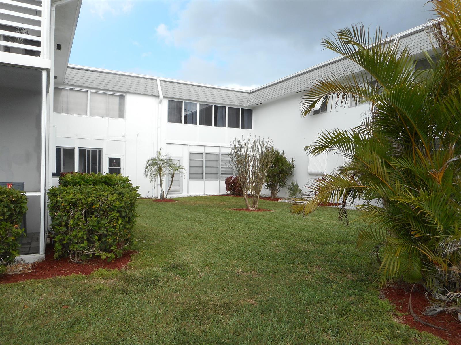 A grassy courtyard sits between the two wings of a white two-story apartment building — 3322 Cynthia Lane # 106, FL 33461, FL