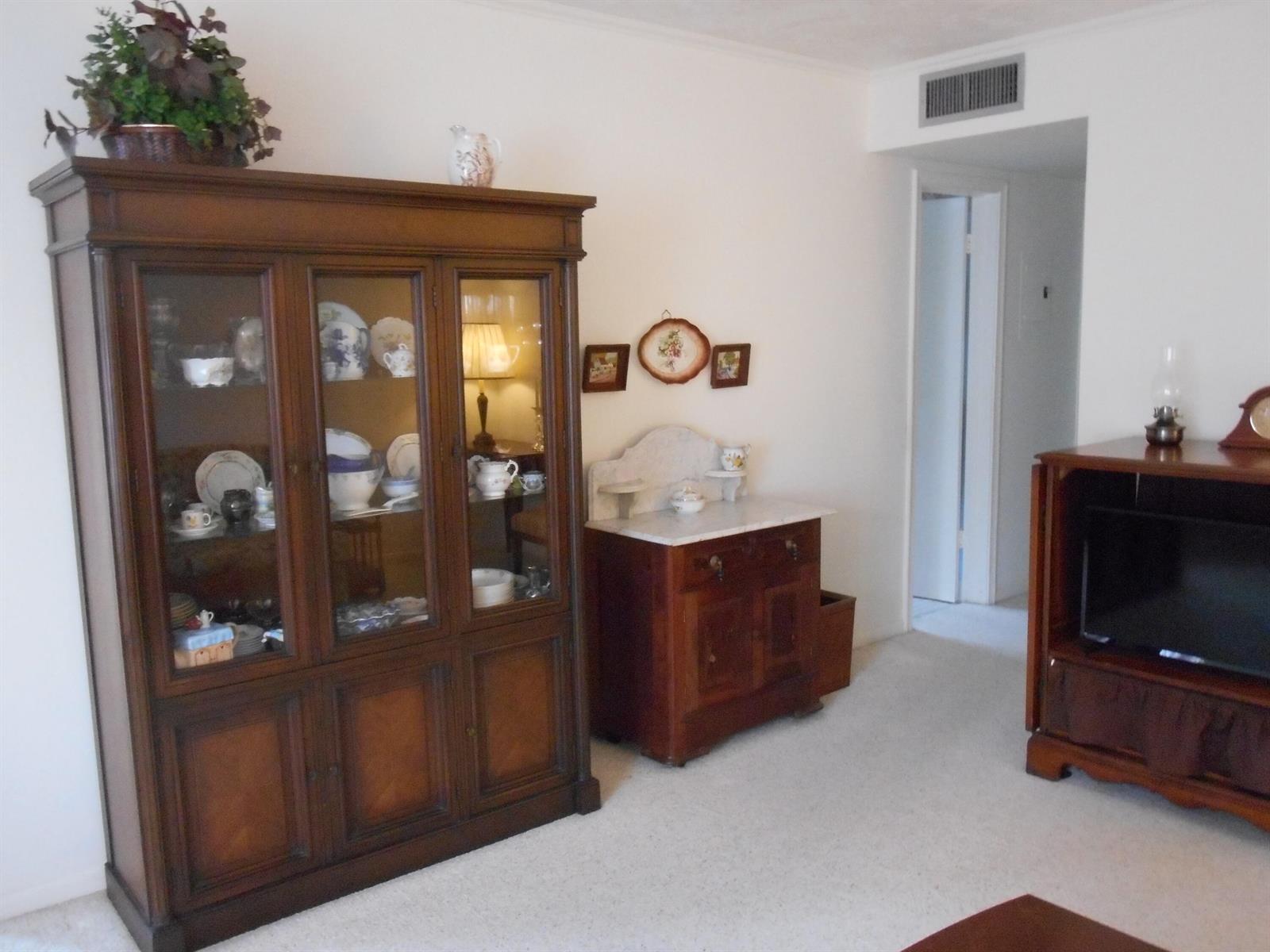 A living room features a large wooden china cabinet, a marble-top sideboard, and carpeted flooring — 3322 Cynthia Lane # 106, FL 33461, FL