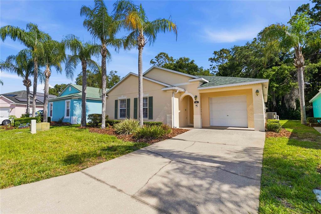 A single-story house with a beige exterior, a one-car garage, and palm trees in front — 446 RESERVE DRIVE, DAVENPORT, FL