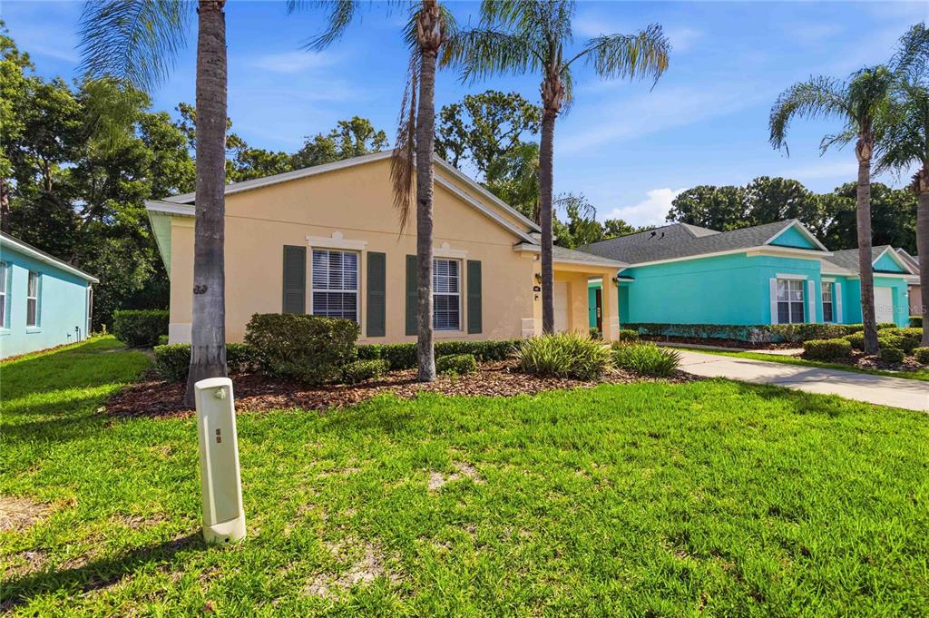 A tan house with dark shutters stands next to a bright turquoise house — 446 RESERVE DRIVE, DAVENPORT, FL