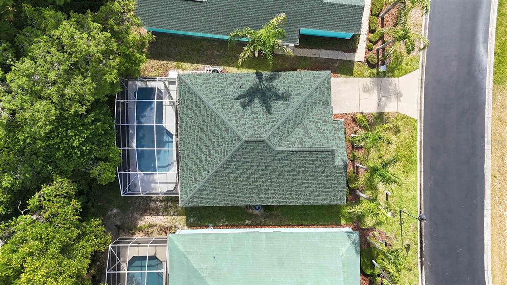 An aerial view shows a house with a green roof, a pool cage, and landscaping — 446 RESERVE DRIVE, DAVENPORT, FL
