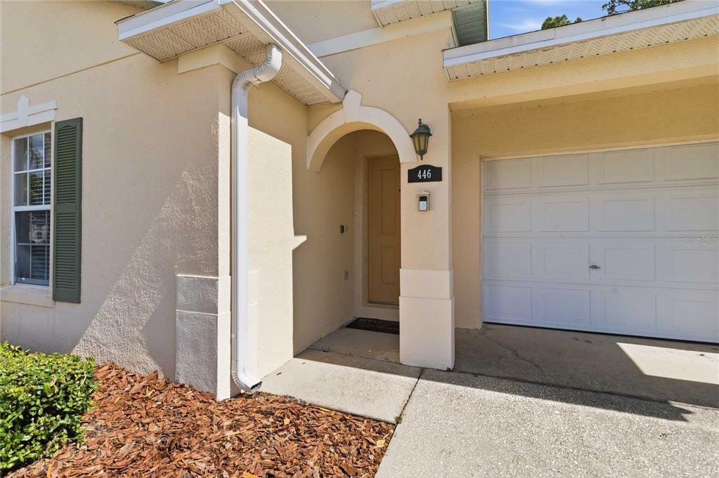 The exterior of a beige house features a covered entryway, a garage, and a downspout — 446 RESERVE DRIVE, DAVENPORT, FL