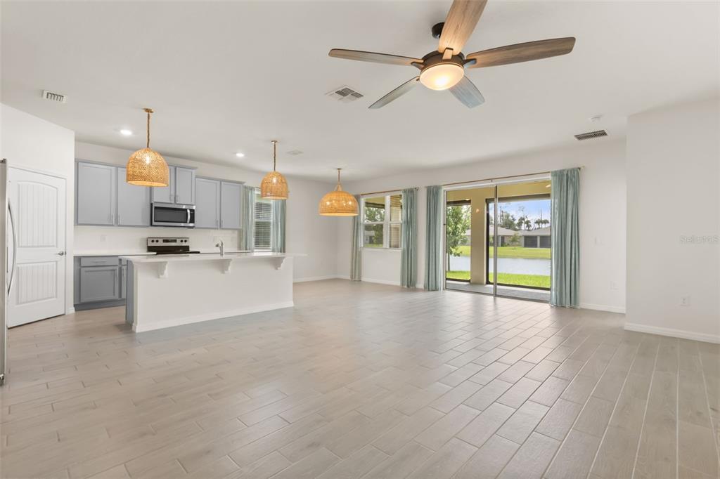 An open-concept kitchen and living area features light gray cabinets, a kitchen island, and tile flooring — 1545 DELPHI WAY, NEW SMYRNA BEACH, FL