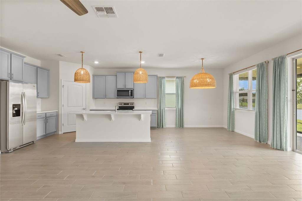 A kitchen with light blue cabinets, a white island, and woven pendant lights over wood-look floors — 1545 DELPHI WAY, NEW SMYRNA BEACH, FL