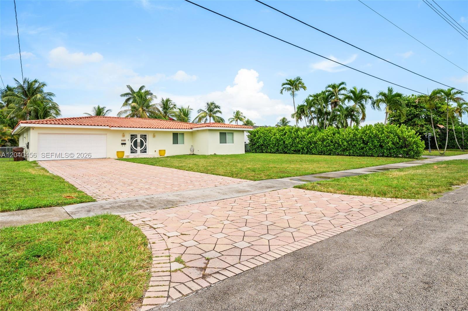 A single-story house with a tiled roof, paved driveway, and a large front lawn — 6185 W 10th Ave, Hialeah FL 33012, HIALEAH, FL