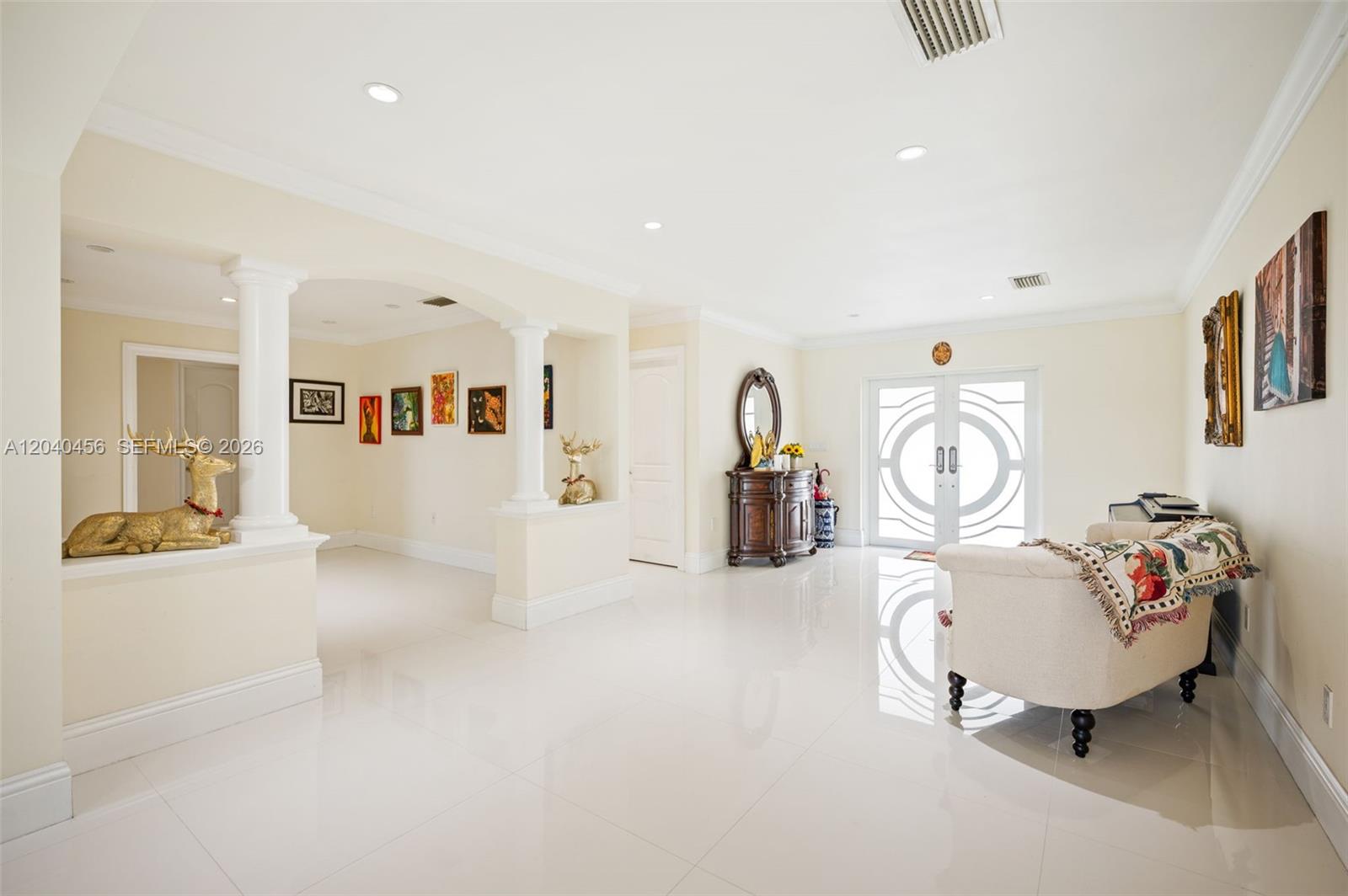 A bright, spacious foyer features white tile floors, decorative columns, and a double glass door — 6185 W 10th Ave, Hialeah FL 33012, HIALEAH, FL