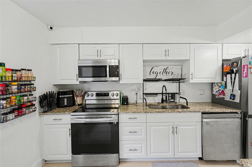 A kitchen with white cabinets, stainless steel appliances, and granite countertops — 1819 CLEARBROOKE DRIVE, CLEARWATER, FL