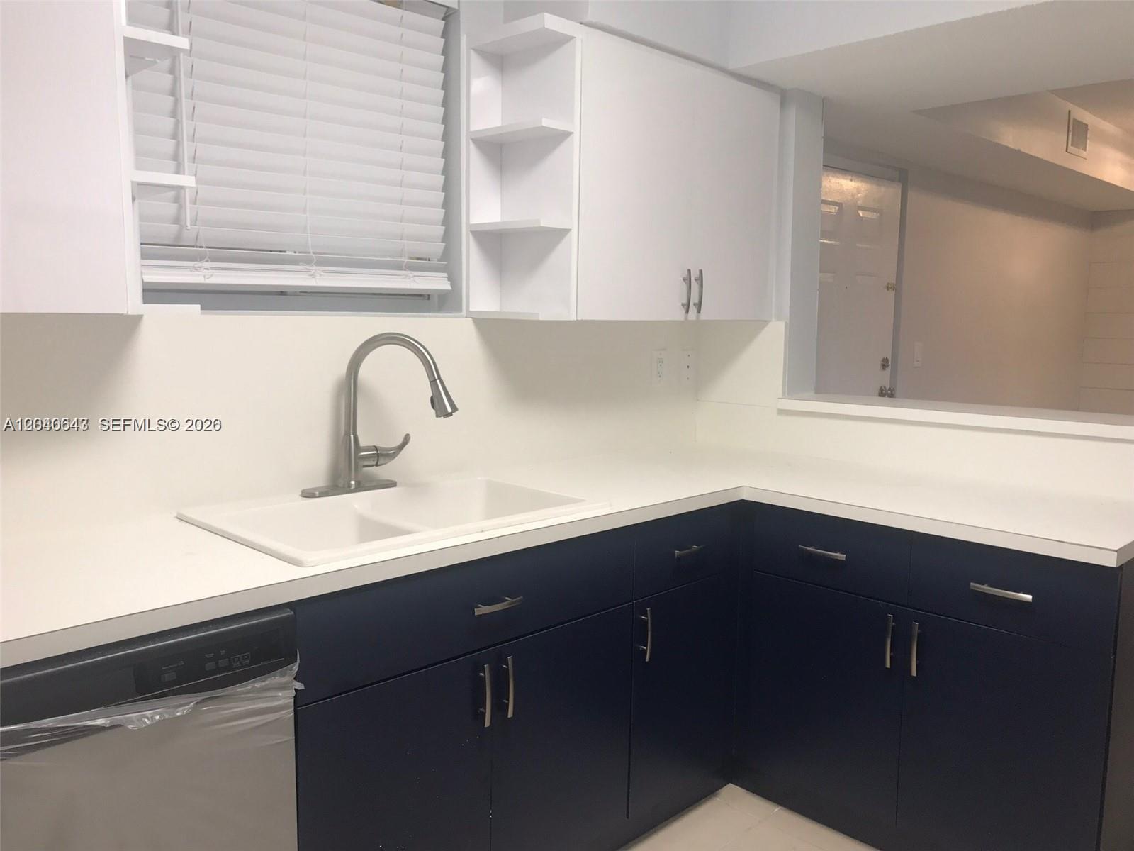 A kitchen features dark blue lower cabinets, white upper cabinets, and a white countertop — 14971 SW 82nd Ln # 308, Miami FL 33193, MIAMI, FL