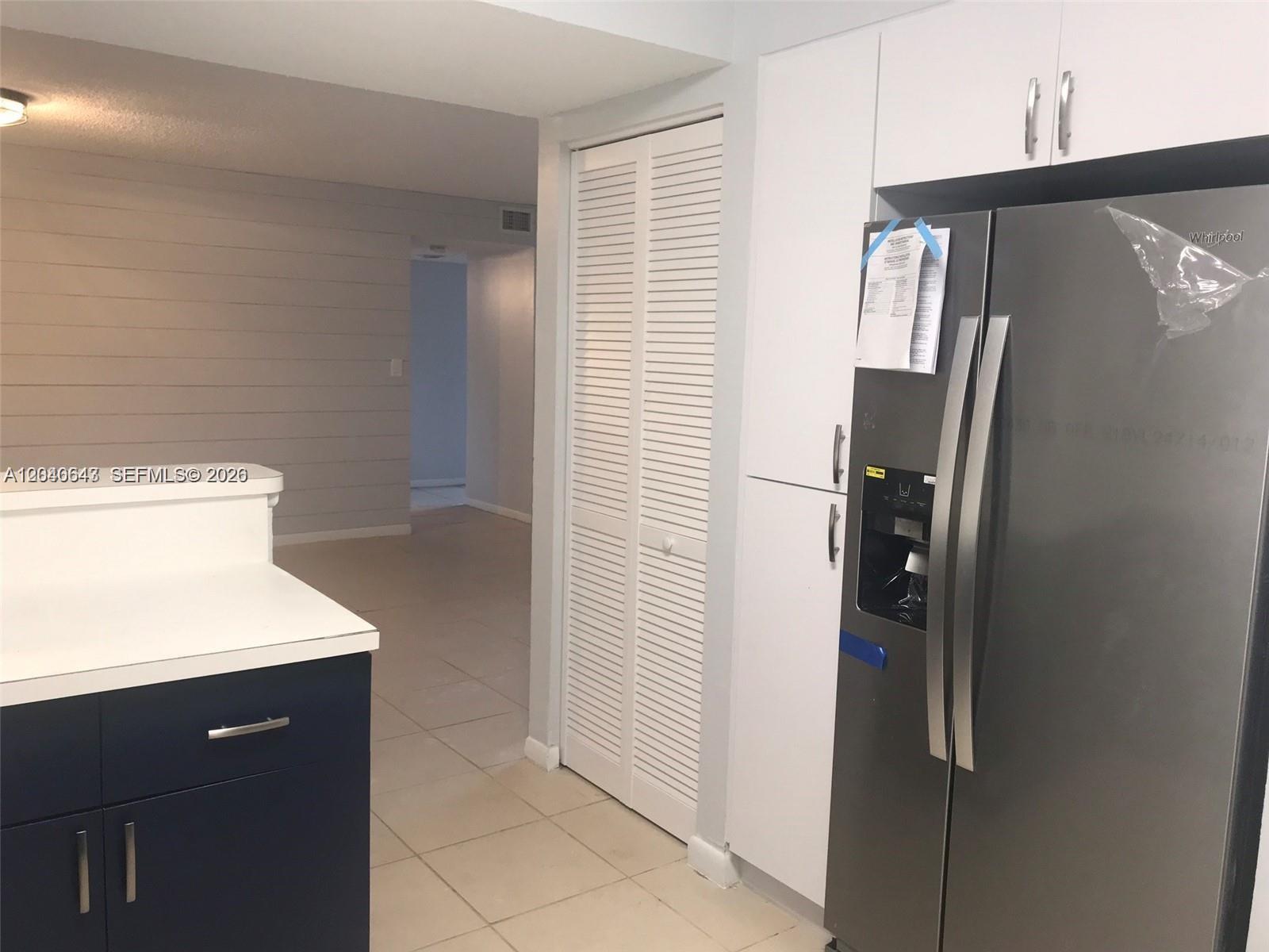 A kitchen features dark blue cabinets, a stainless steel refrigerator, and a louvered closet door — 14971 SW 82nd Ln # 308, Miami FL 33193, MIAMI, FL