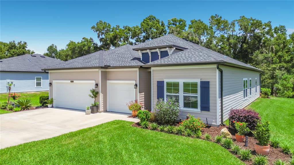 A single-story house with a two-car garage, beige siding, and blue shutters — 19535 SW 77TH LOOP, DUNNELLON, FL
