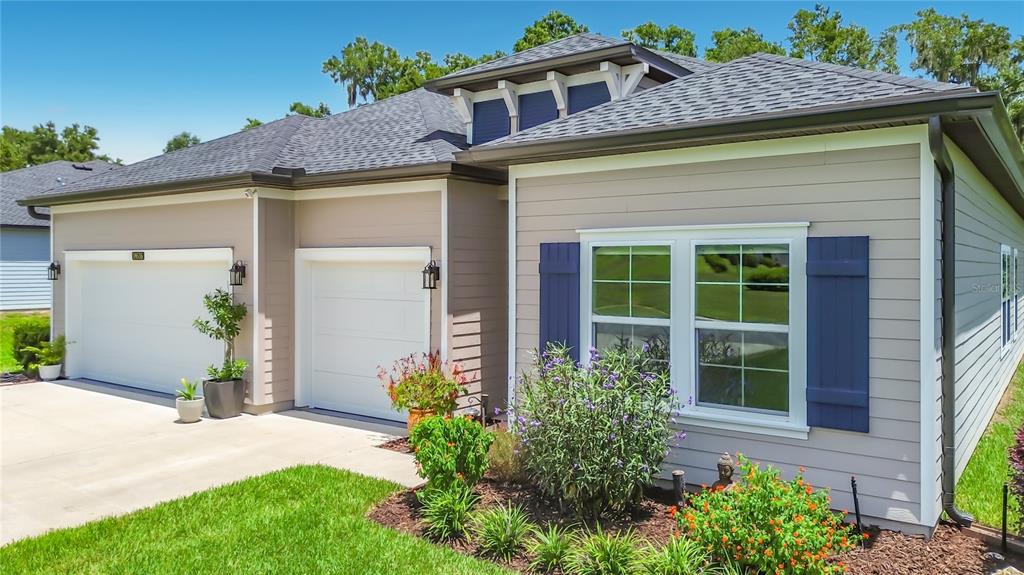 A single-story house with a two-car garage, light siding, and blue shutters — 19535 SW 77TH LOOP, DUNNELLON, FL